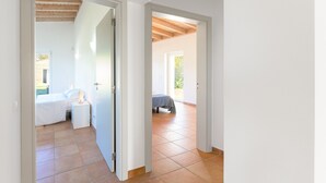 A corridor with a bed and nightstand in one room and a bed in another.