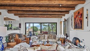 A cozy living room with a fireplace, leather furniture, and a large window offering a scenic view. - Stunning Views, Southwestern Elegance (Santa Fe)