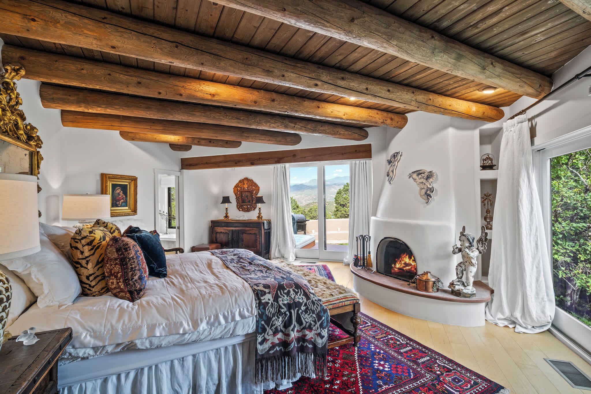 Un dormitorio con una cama grande, chimenea y vistas al exterior.
