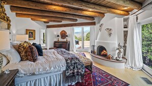 A bedroom with a large bed, a fireplace, and a view of the outdoors. - Stunning Views, Southwestern Elegance (Santa Fe)
