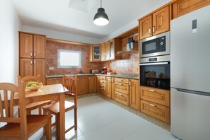 Une cuisine avec des meubles de rangement en bois, un réfrigérateur blanc et un four à micro-ondes.
