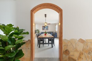 Un coin repas avec une table et des chaises en bois, une plante en pot et un mur en pierre.