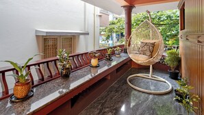 A spacious balcony with a hanging chair, potted plants, and a marble floor.