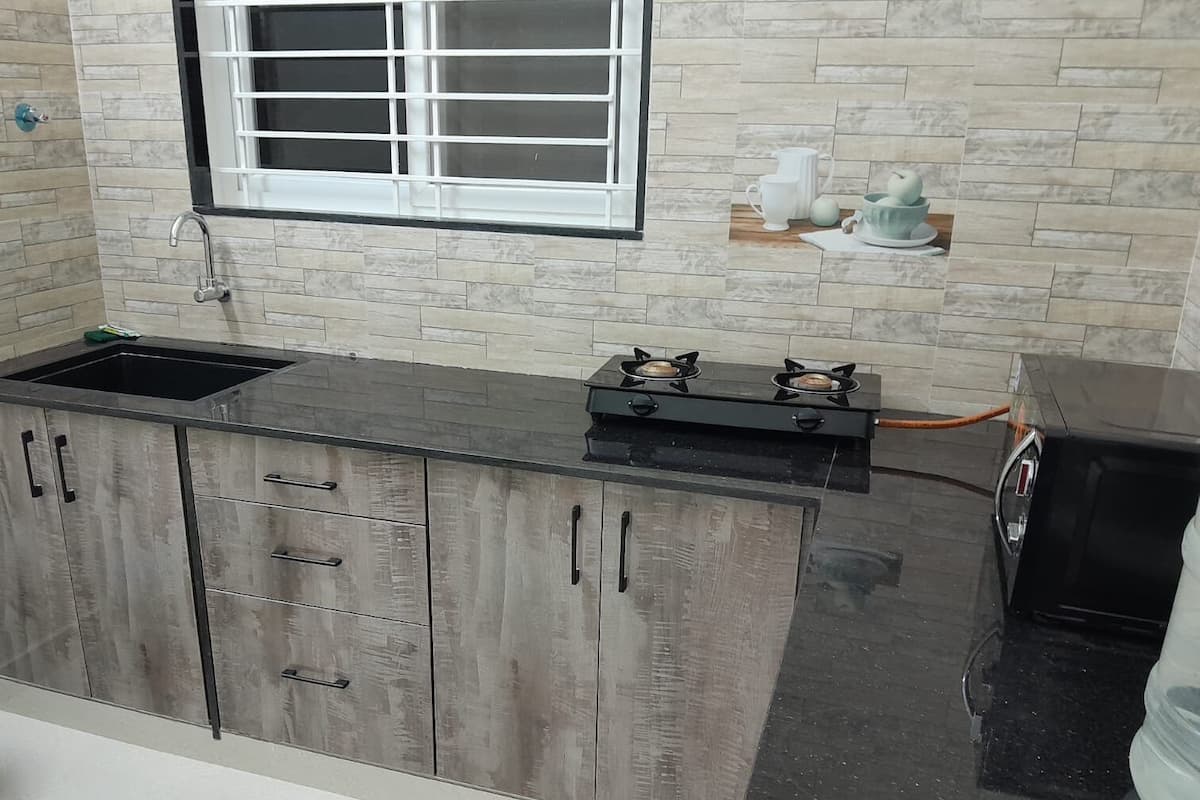 A kitchen with a black countertop, a sink, a stove, and wooden cabinets.