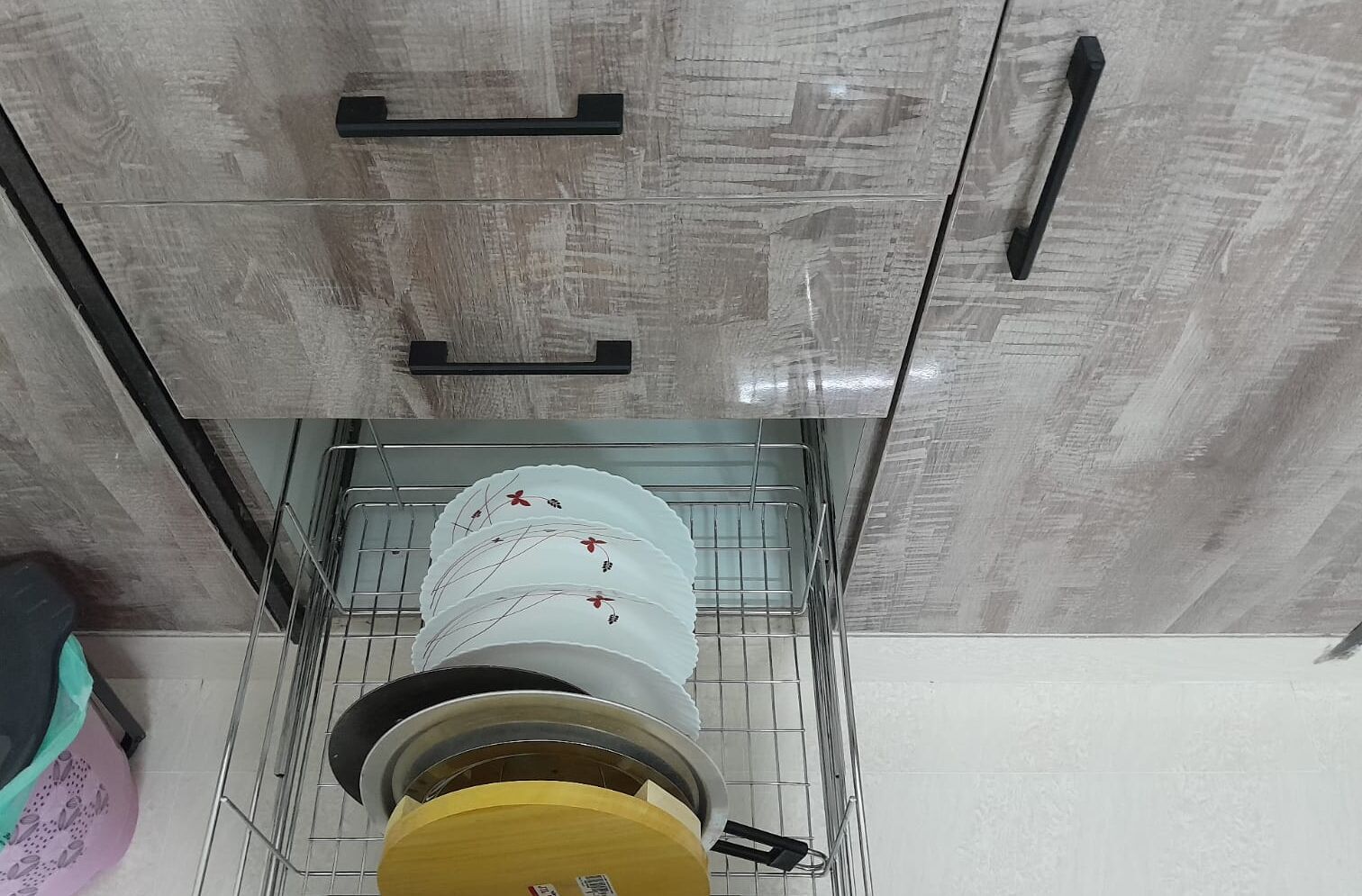 A kitchen with a stainless steel sink, a yellow countertop, and a white cabinet with a handle.