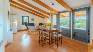 A dining area with a round table, chairs, and a hanging light fixture. - Country House 'Vinyoles 2' with Mountain View, Shared Pool and Wi-Fi (Quart)