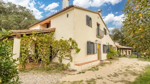 A two-story house with a balcony, a garden, and a gravel driveway. - Country House 'Vinyoles 2' with Mountain View, Shared Pool and Wi-Fi (Quart)