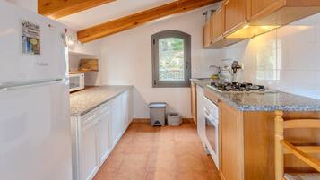 Una cocina con armarios blancos, encimera de granito, techo de madera y una ventana.