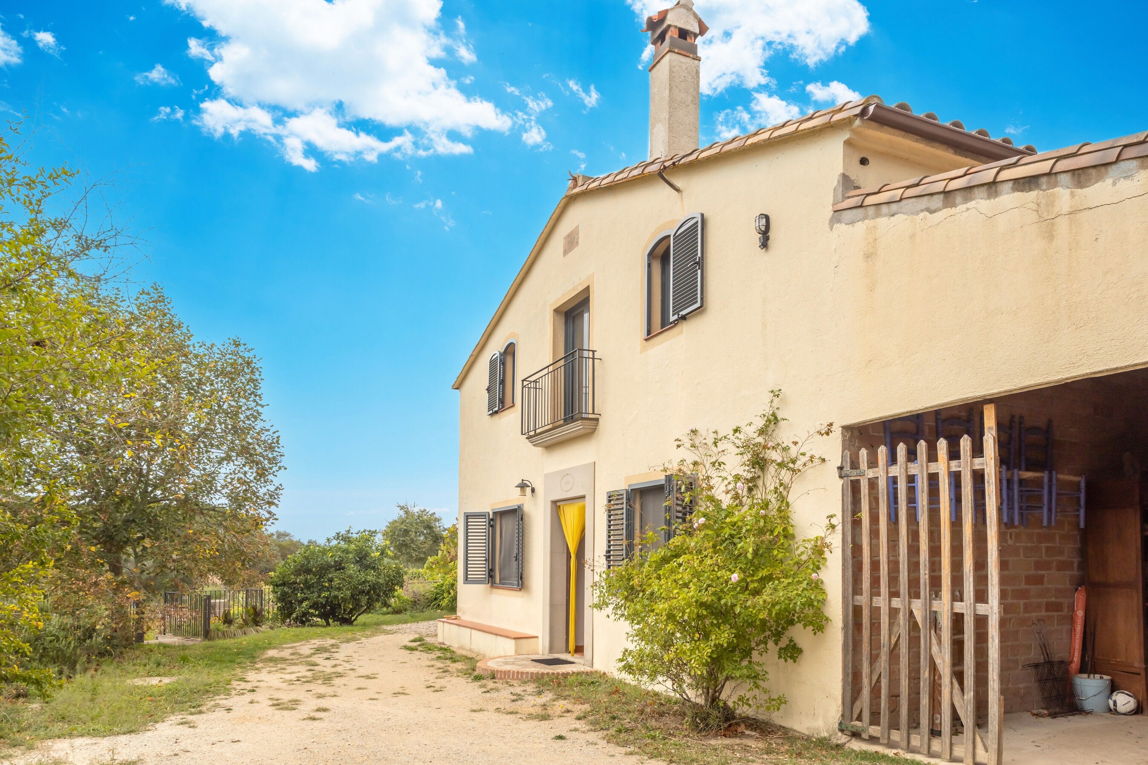 Una casa de dos pisos con balcón, garaje y entrada de tierra.