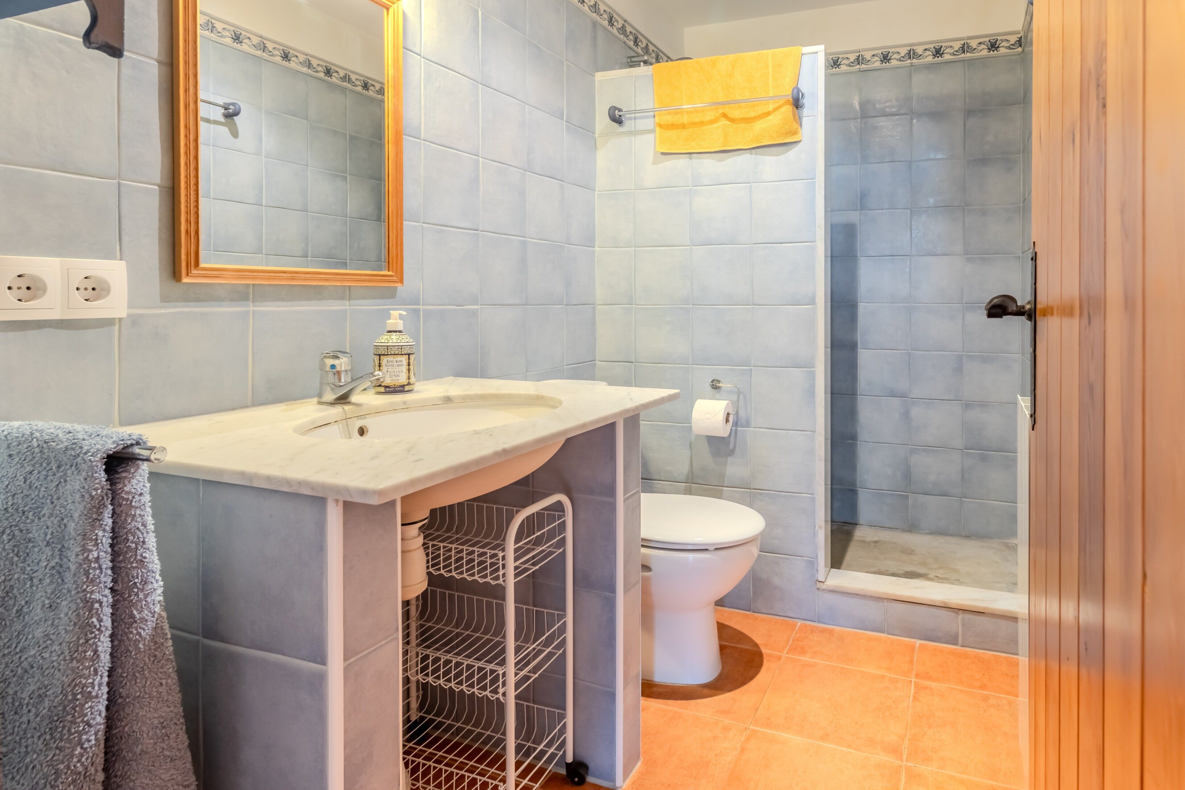 A bathroom with a sink, mirror, toilet, and shower.