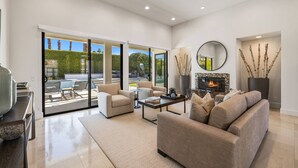 A spacious living room with a fireplace, comfortable seating, and large sliding glass doors leading to an outdoor area.