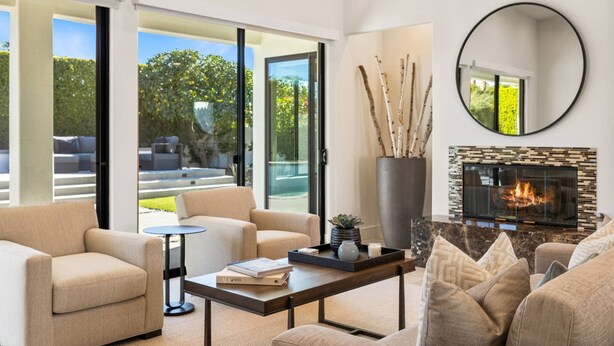 A modern living room with a fireplace, comfortable seating, and a view of the outdoors.