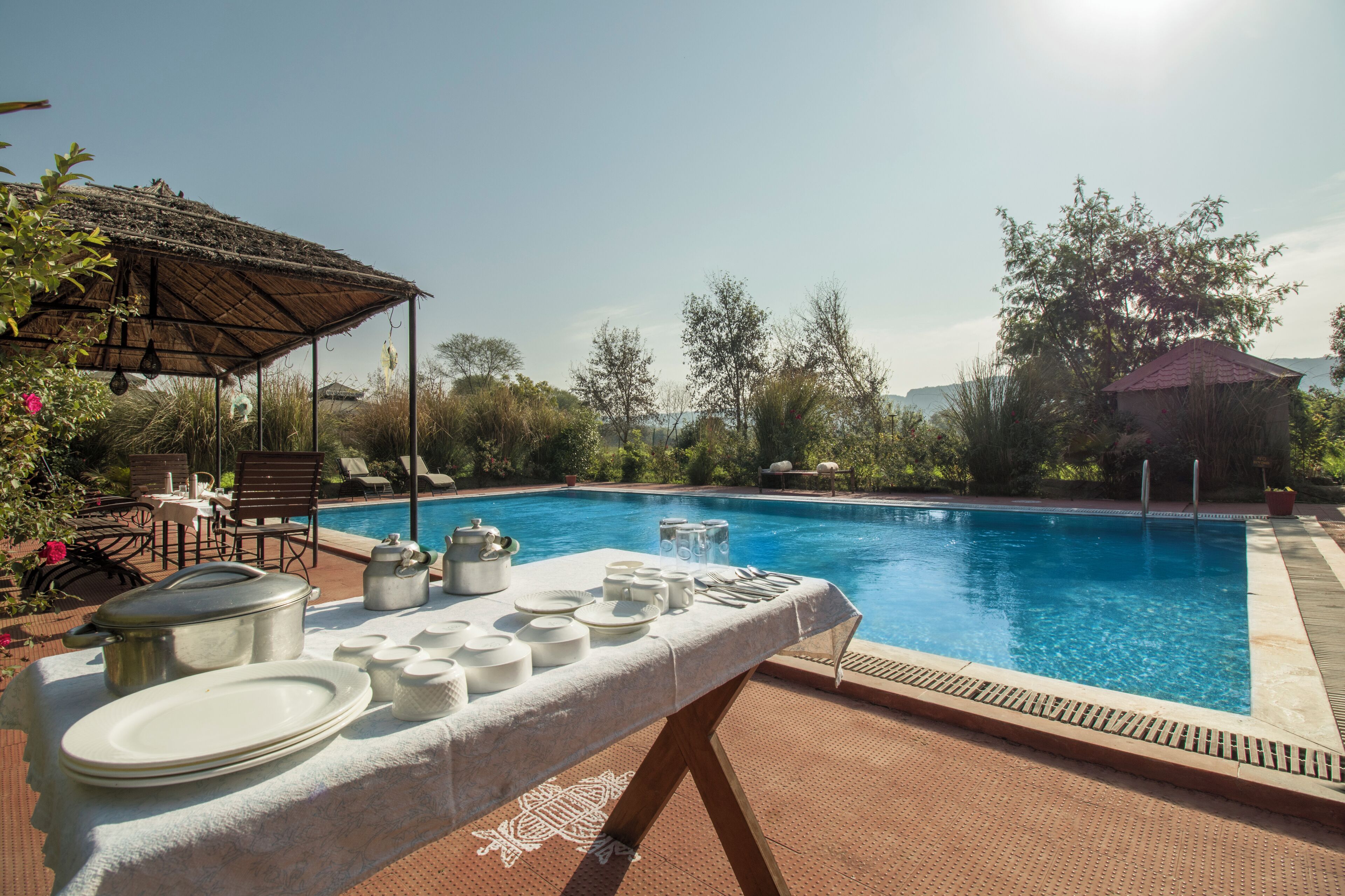 A poolside dining setup with a table set for service, overlooking a swimming pool.
