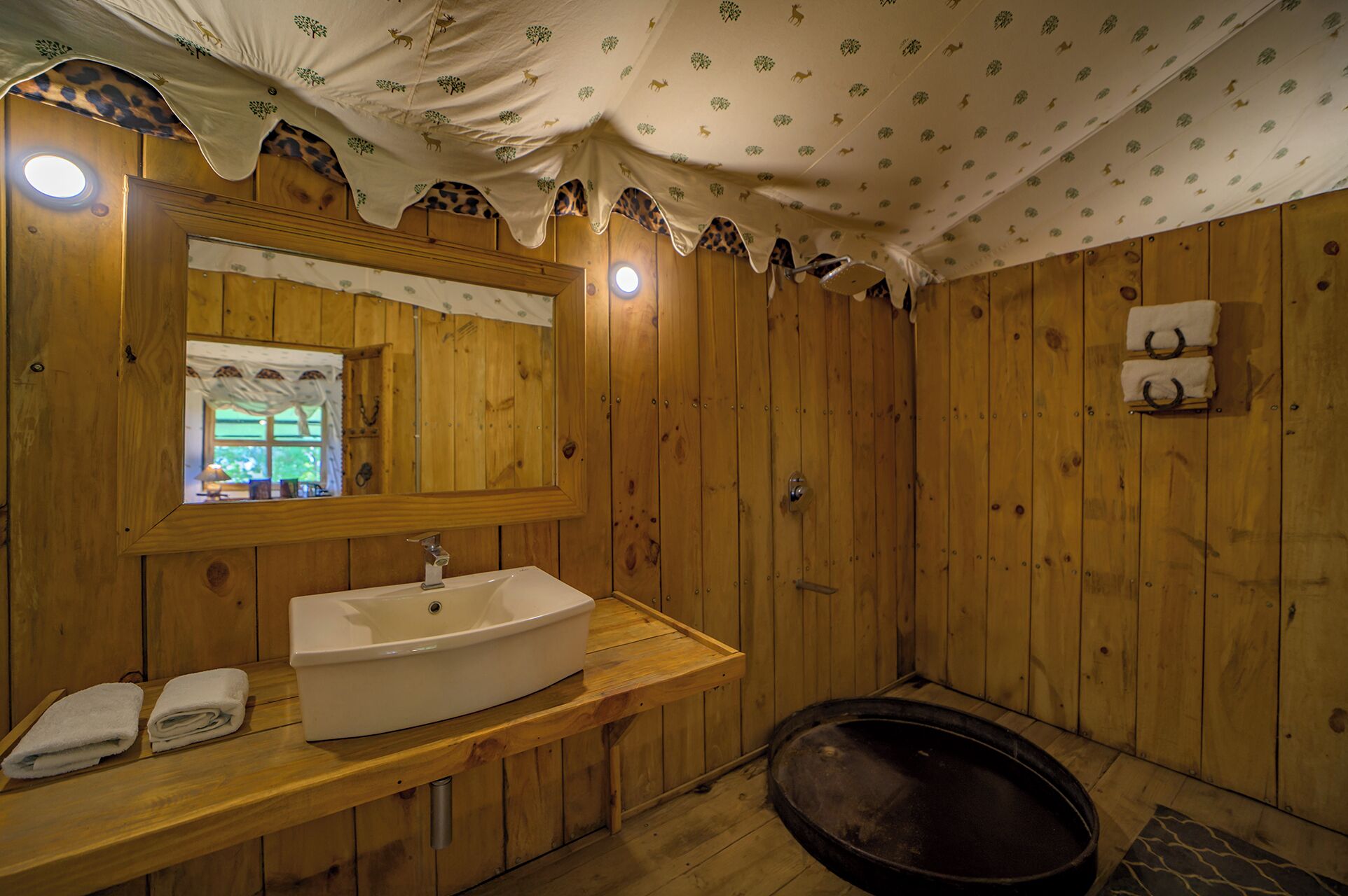 A wooden bathroom with a large sink, mirror, and a shower area.