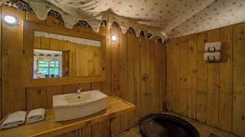 A wooden bathroom with a large sink, mirror, and a shower area.