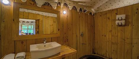 A wooden bathroom with a large sink, mirror, and a shower area.
