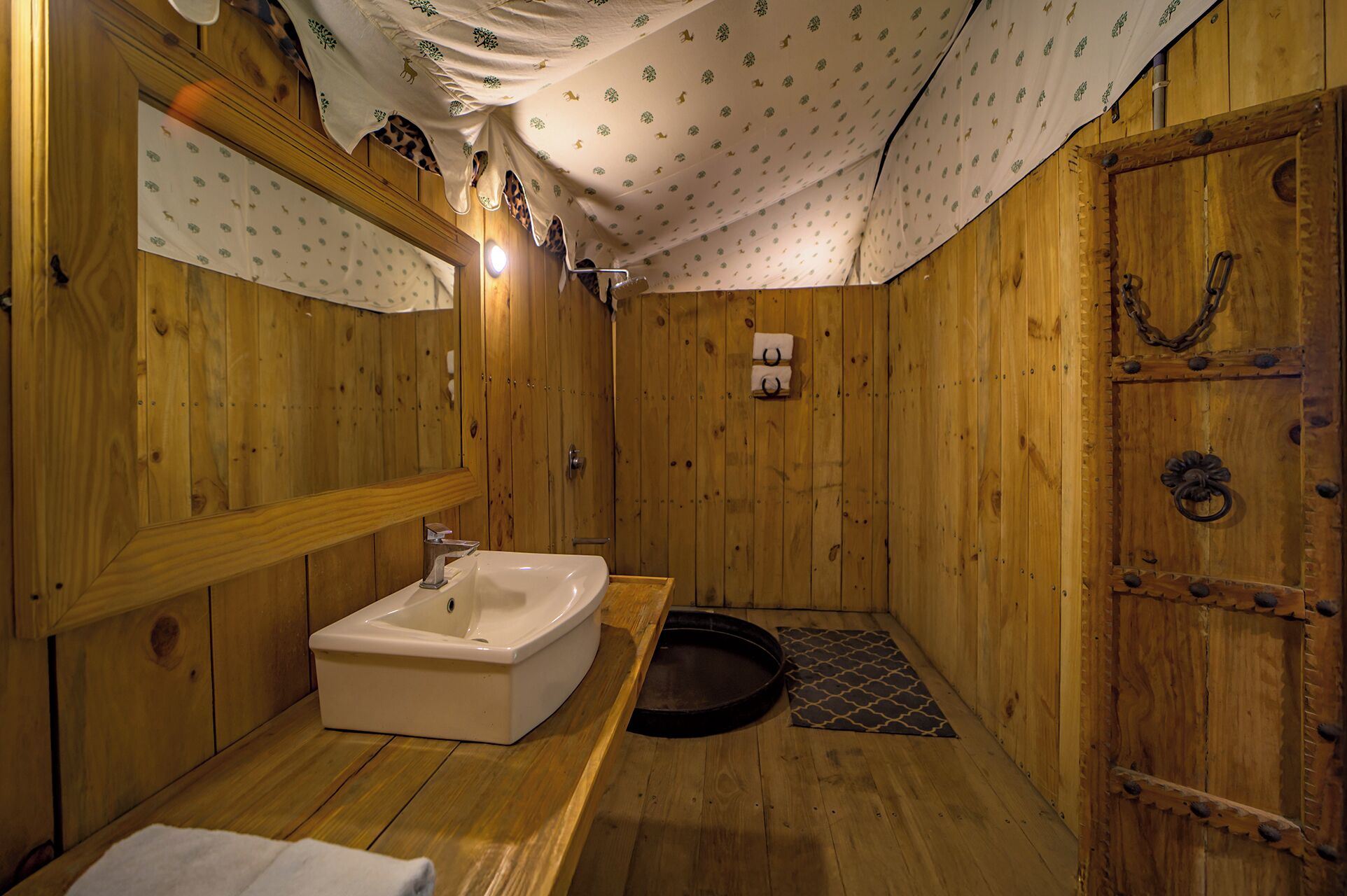 A wooden cabin-style bathroom with a sink, mirror, and shower area.