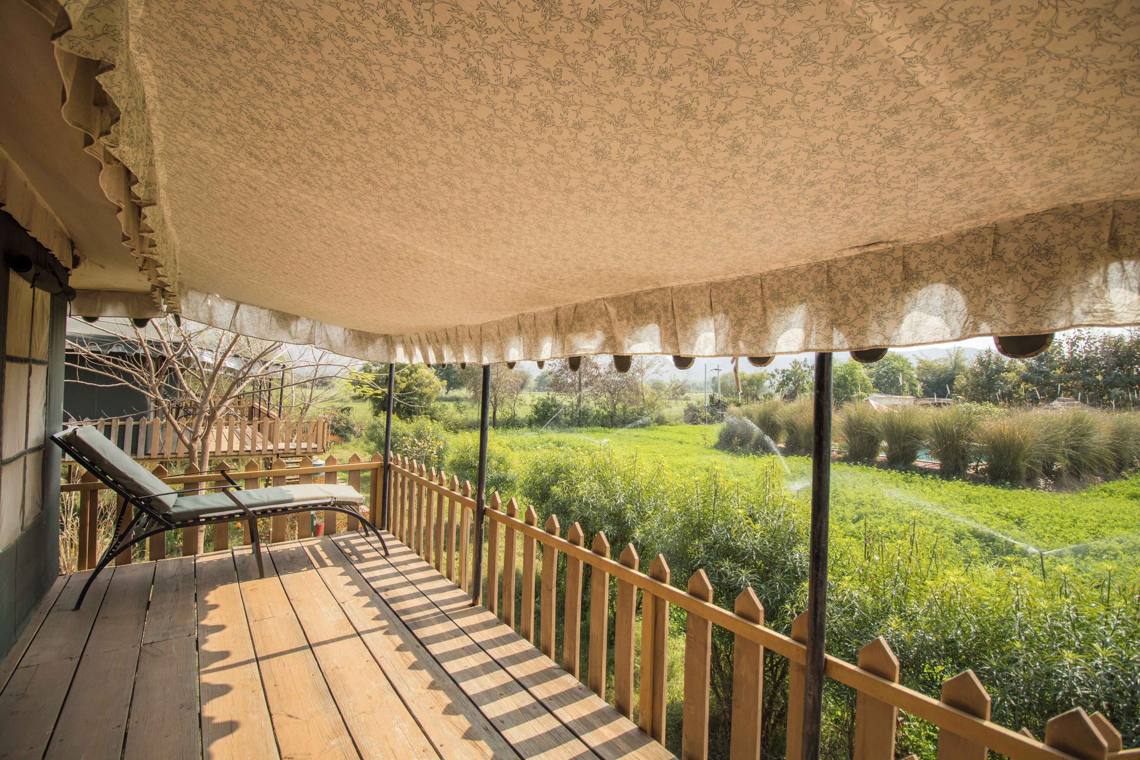 A wooden deck with a checkered floor, a wooden railing, and a canopy overhead.