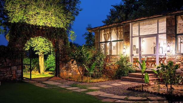 A stone building with large windows, a stone pathway, and a tree with hanging vines. - Maa Ashapura Resort (Sawai Madhopur)