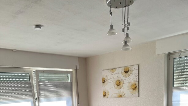 A living room with a sectional sofa, a coffee table, and a radiator. - Red Dot Eva (Werne)