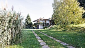 Una casa con un sendero de piedra que lleva a la entrada, rodeada de vegetación y árboles.