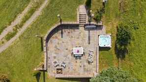 An aerial view of a patio area with a hot tub, a table with chairs, and a fire pit. - Sojourners Rest: Old Rag Views, Hot Tub, Fire Pit (Etlan)