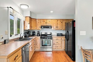 A modern kitchen with wooden cabinets, stainless steel appliances, and a dishwasher. - Sojourners Rest: Old Rag Views, Hot Tub, Fire Pit (Etlan)