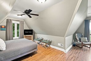 A bedroom with a bed, a TV, a ceiling fan, and a window with curtains. - Sojourners Rest: Old Rag Views, Hot Tub, Fire Pit (Etlan)