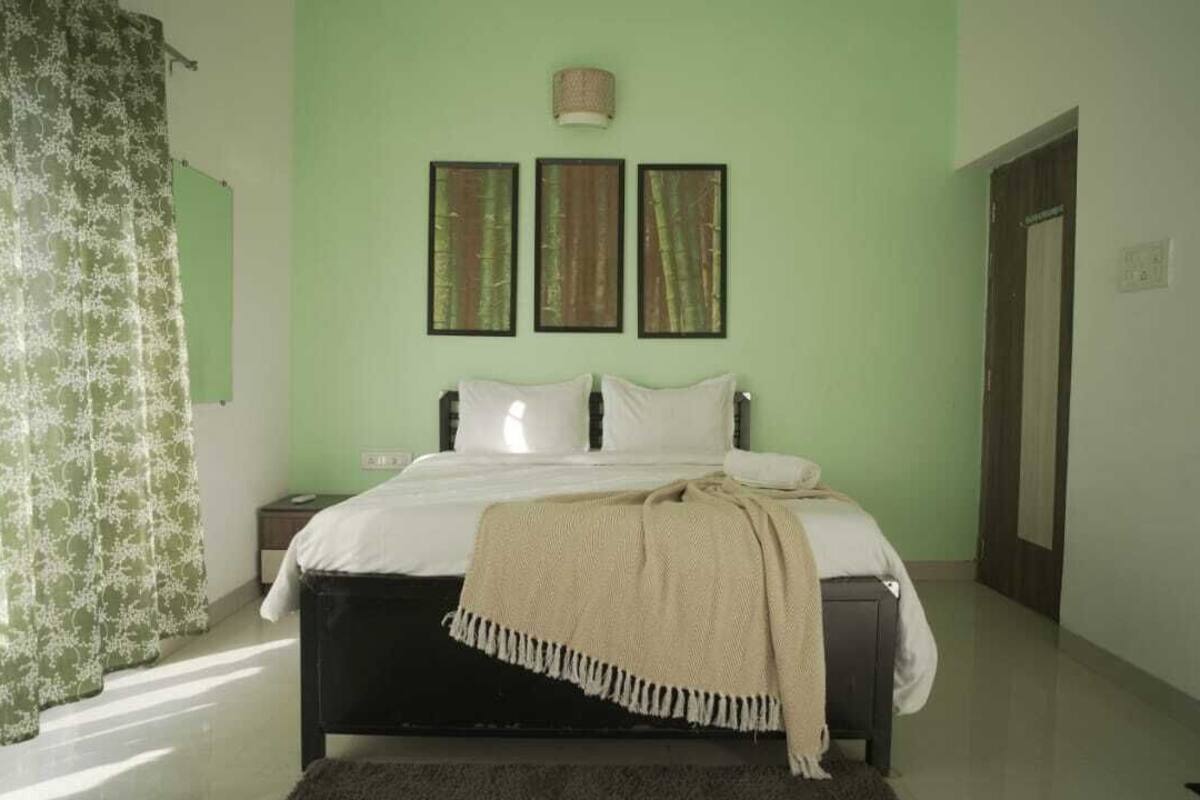 Ein Schlafzimmer mit einem Bett, einem Nachttisch und einer Lampe. An der Wand hängen drei Bilder in Rahmen.