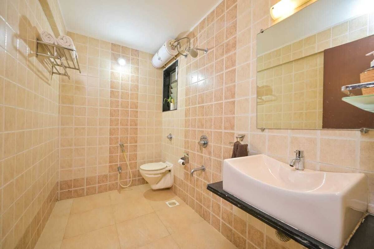 Ein Badezimmer mit beige farbenen Fliesen, einem weißen Waschbecken, einer Toilette und einer Dusche.