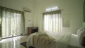 Ein Schlafzimmer mit einem Bett, einem Nachttisch, einem Spiegel und Vorhängen.