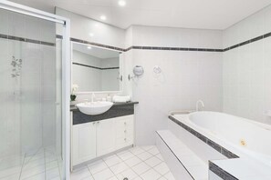 Un baño moderno con cabina de ducha de vidrio, una bañera independiente y un lavabo con mueble.