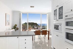 Una cocina moderna con armarios blancos, encimera de granito y vistas al mar.
