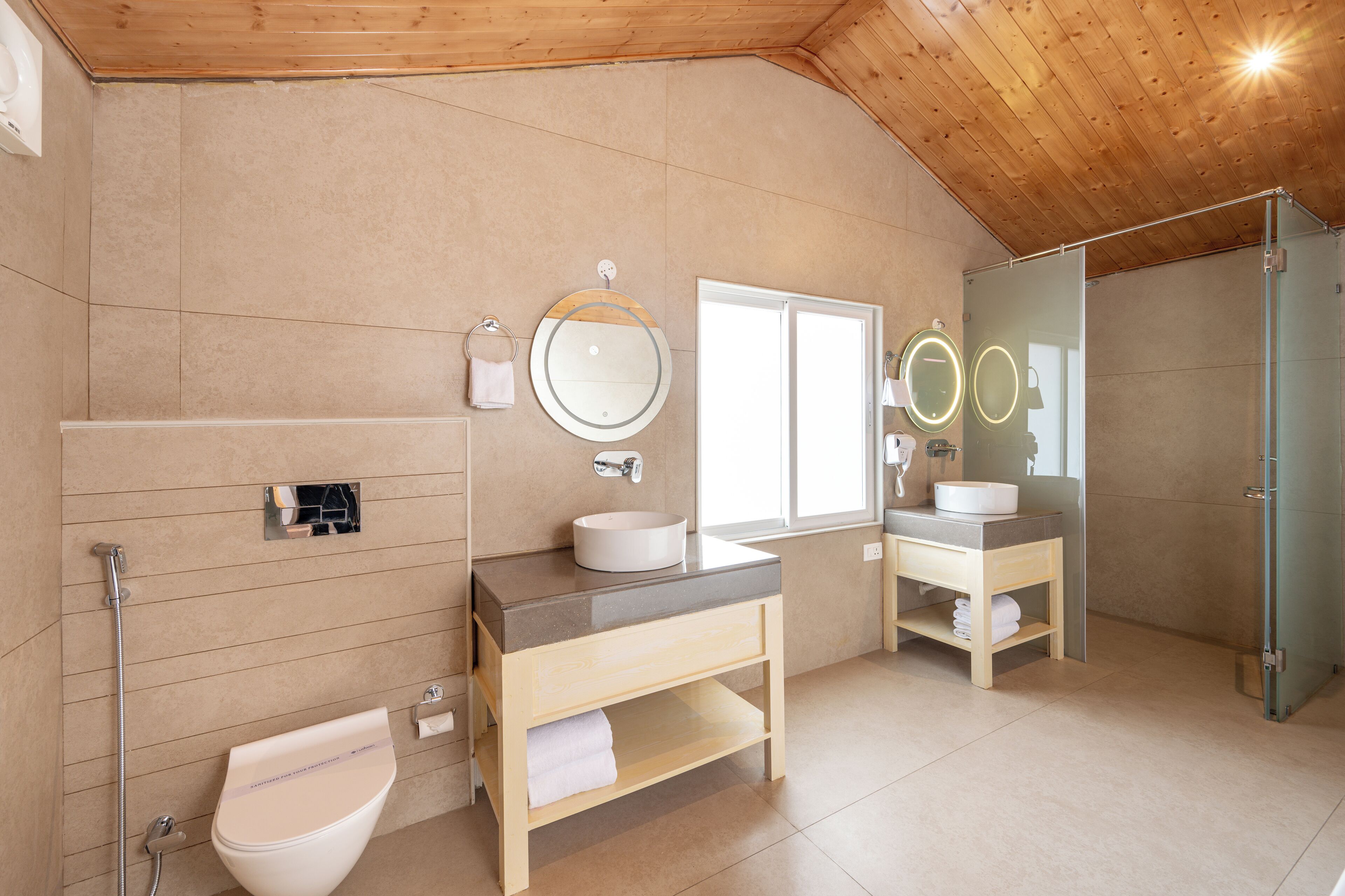 A modern bathroom with two sinks, a toilet, and a shower.