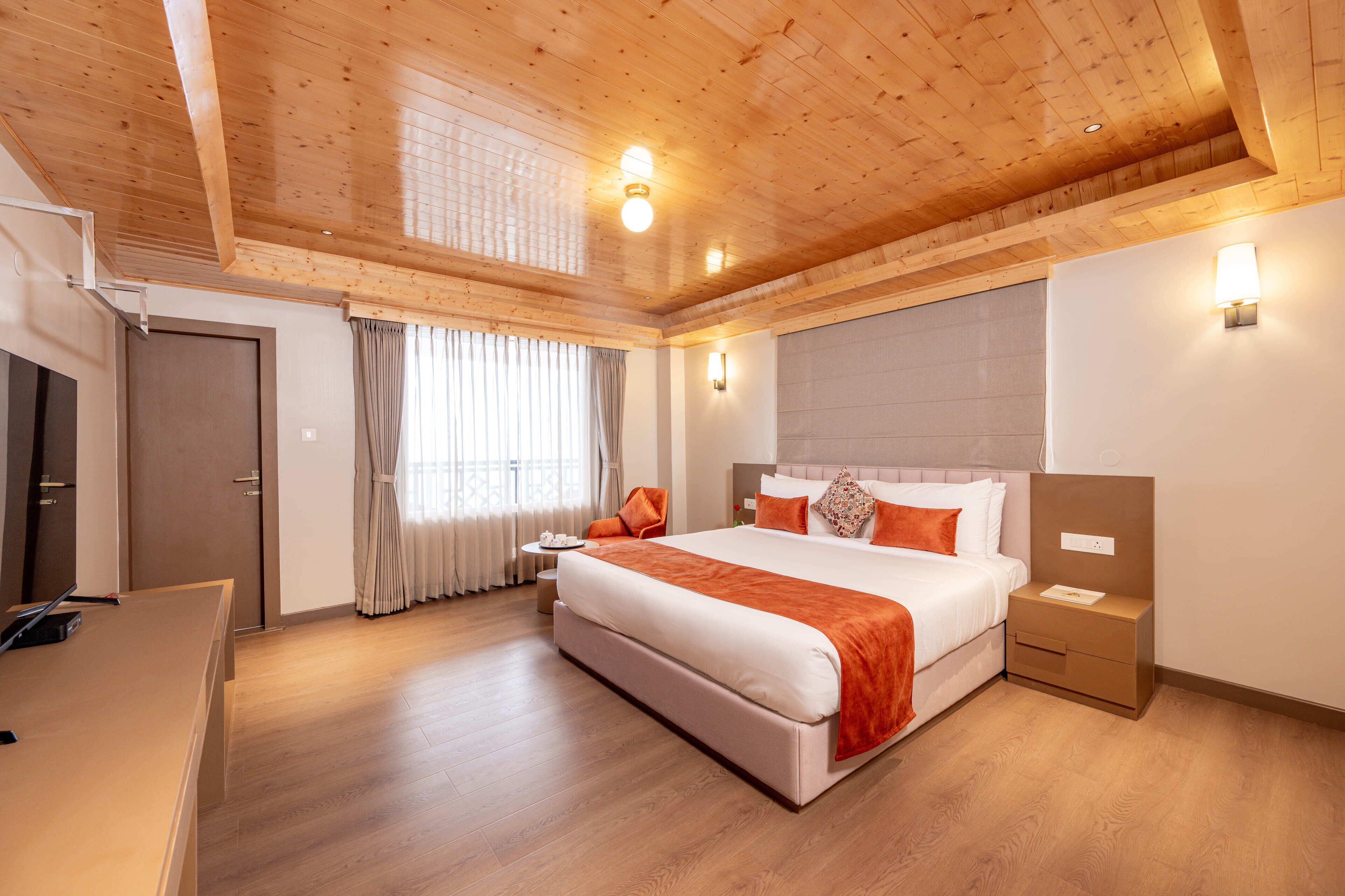 Un dormitorio espacioso con una cama grande, techo de madera y una mesita de noche con lámpara.