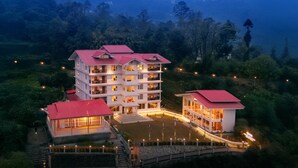 A multi-story hotel with a red roof, surrounded by lush greenery and hills in the background. - Udaan Khang-Chen View Resort & Spa (Gyalshing)