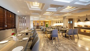 A modern dining area with a long table set for a meal, a bar area with a counter, and a seating area with cushioned chairs. - Udaan Khang-Chen View Resort & Spa (Gyalshing)