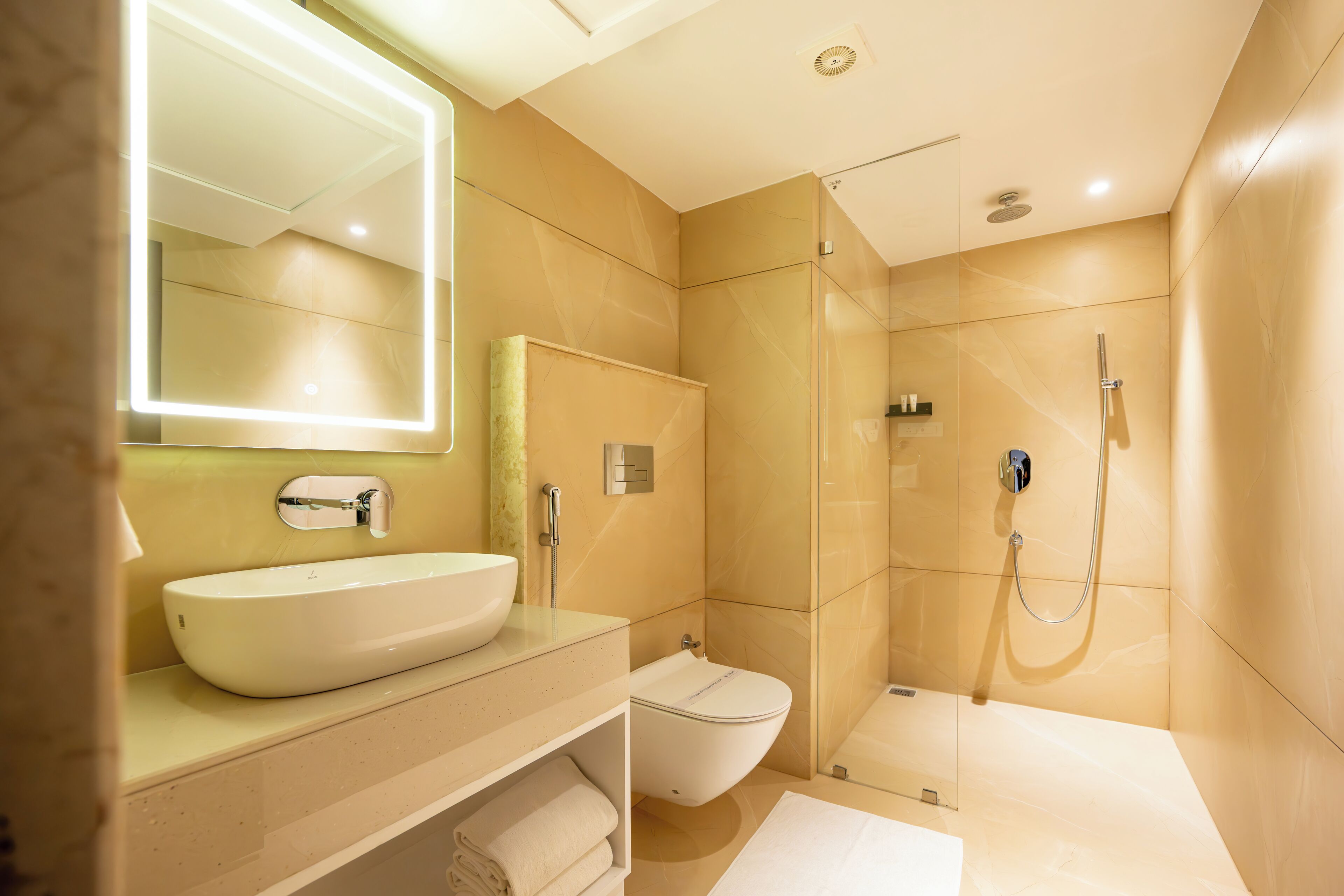 A modern bathroom with a large mirror, a sink, a toilet, and a glass-enclosed shower.