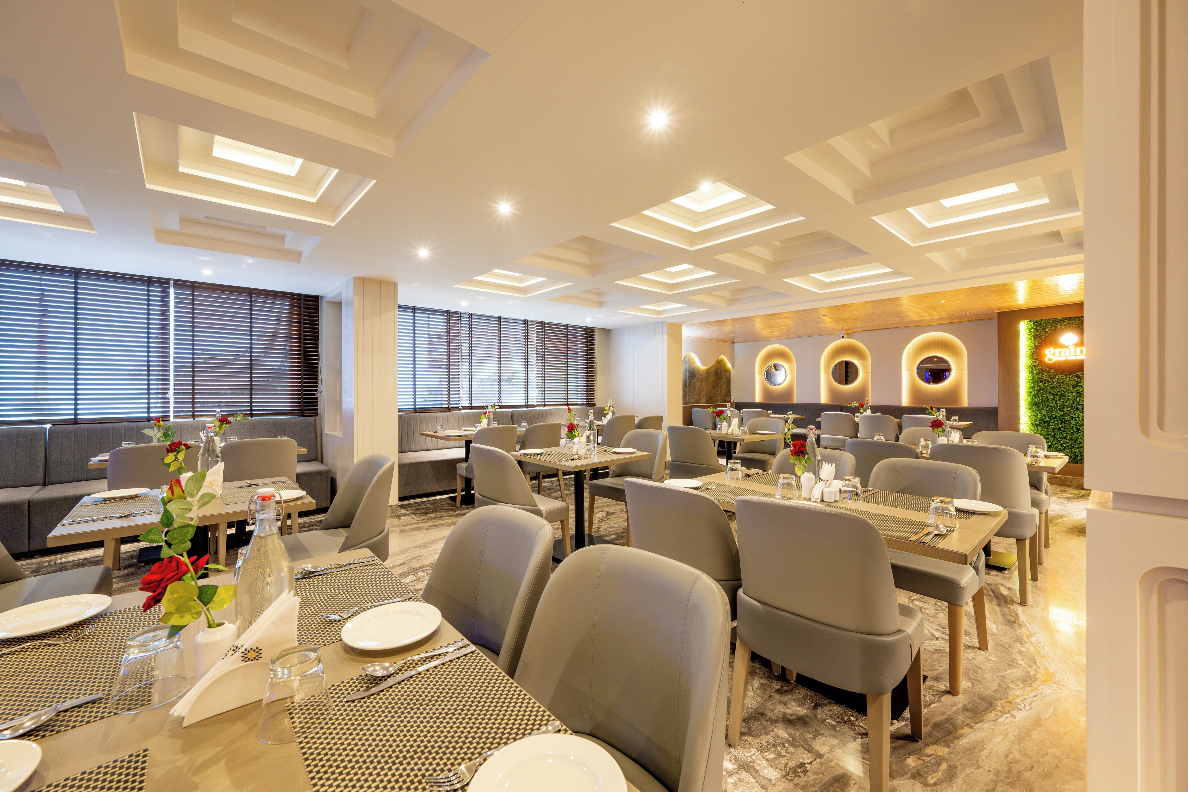A modern dining area with tables set for meals, a seating area with sofas, and a decorative wall with circular designs.