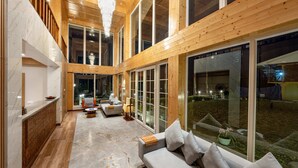A spacious living area with a large sofa, a coffee table, and a chandelier. - Udaan Khang-Chen View Resort & Spa (Gyalshing)