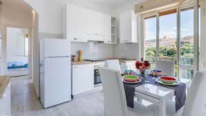 Een moderne keuken met witte kasten, een inbouwoven en een eethoek met een tafel voor twee personen.