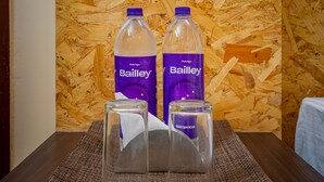 Pöydällä on kaksi Bailey-merkkiä olevaa vesipulloa ja kaksi kirkasta lasia, ja taustalla on puinen seinä.