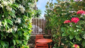 Een tuin met een tafel en stoelen, een waterpartij en een lantaarn.