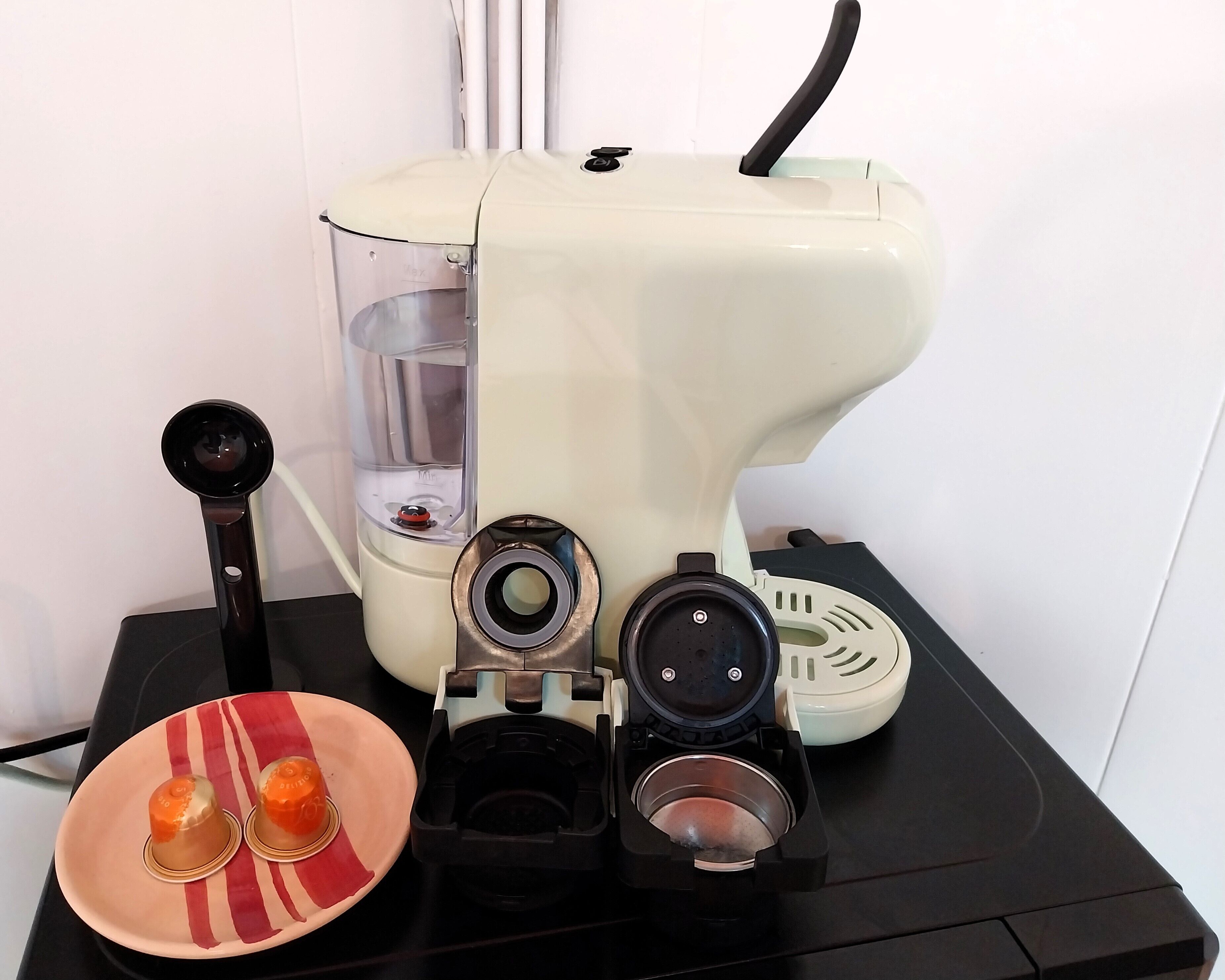 A coffee machine with a water reservoir, a drip tray, and a plate with two cups.