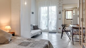 A bedroom with a bed, bedside table, and a view of the dining area. - Apartment 'Un Angolo Nel Verde A Empoli' with Shared Terrace, Wi-Fi and Air Conditioning (Empoli)