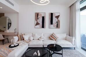 Een moderne woonkamer met een witte bank, een ronde salontafel en abstracte kunst aan de muur.