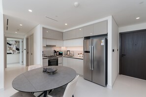 Een moderne keuken met een grote koelkast, een eettafel met stoelen en een keukeneiland.
