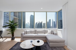 Una sala de estar moderna con un ventanal grande, un sofá modular gris, una mesa de centro redonda y una planta en maceta.