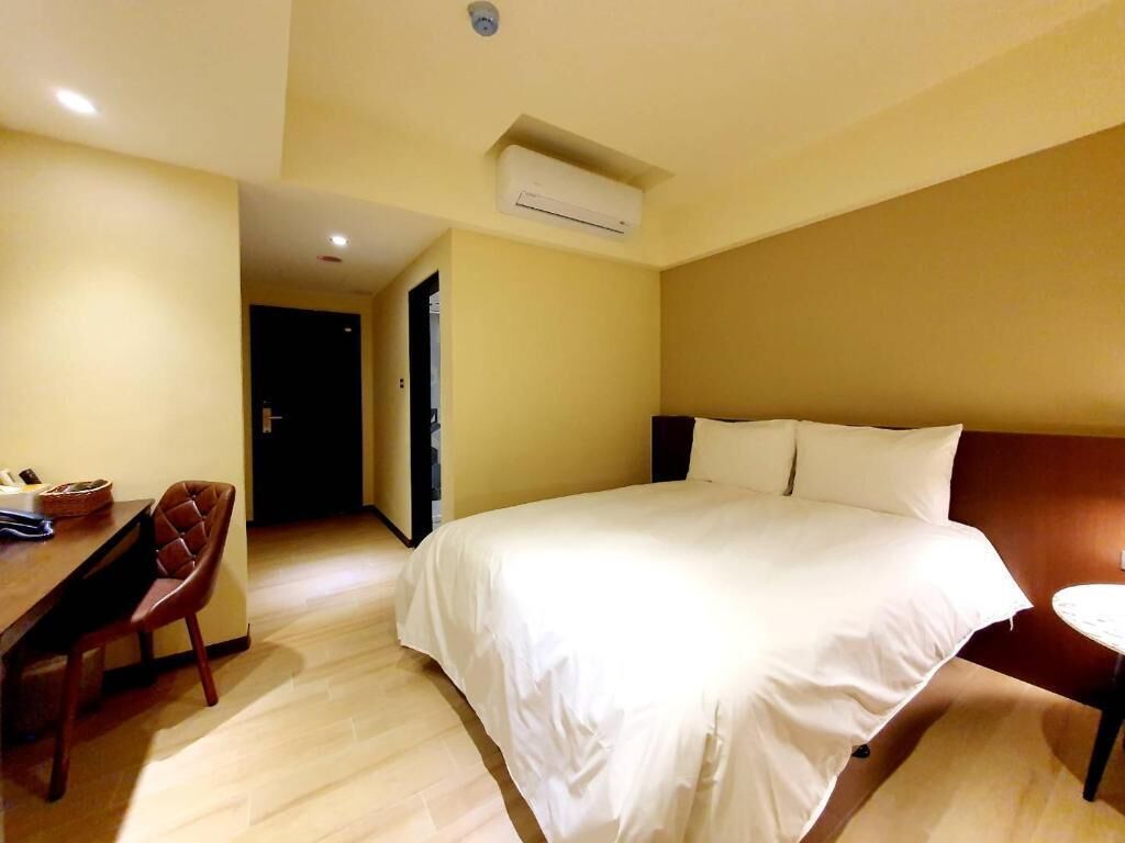 Una habitación de hotel con cama, escritorio y aire acondicionado.
