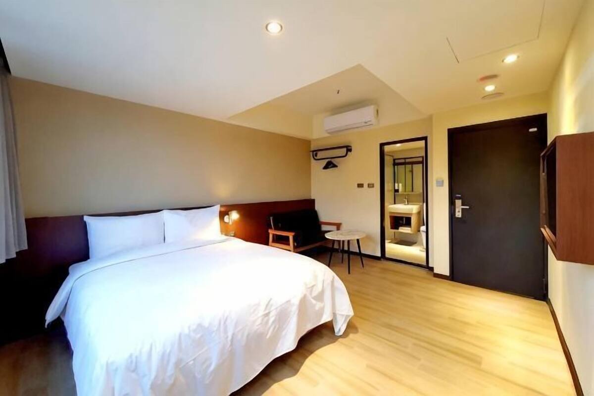 Una habitación de hotel con una cama grande, un escritorio y una puerta que da a un baño.